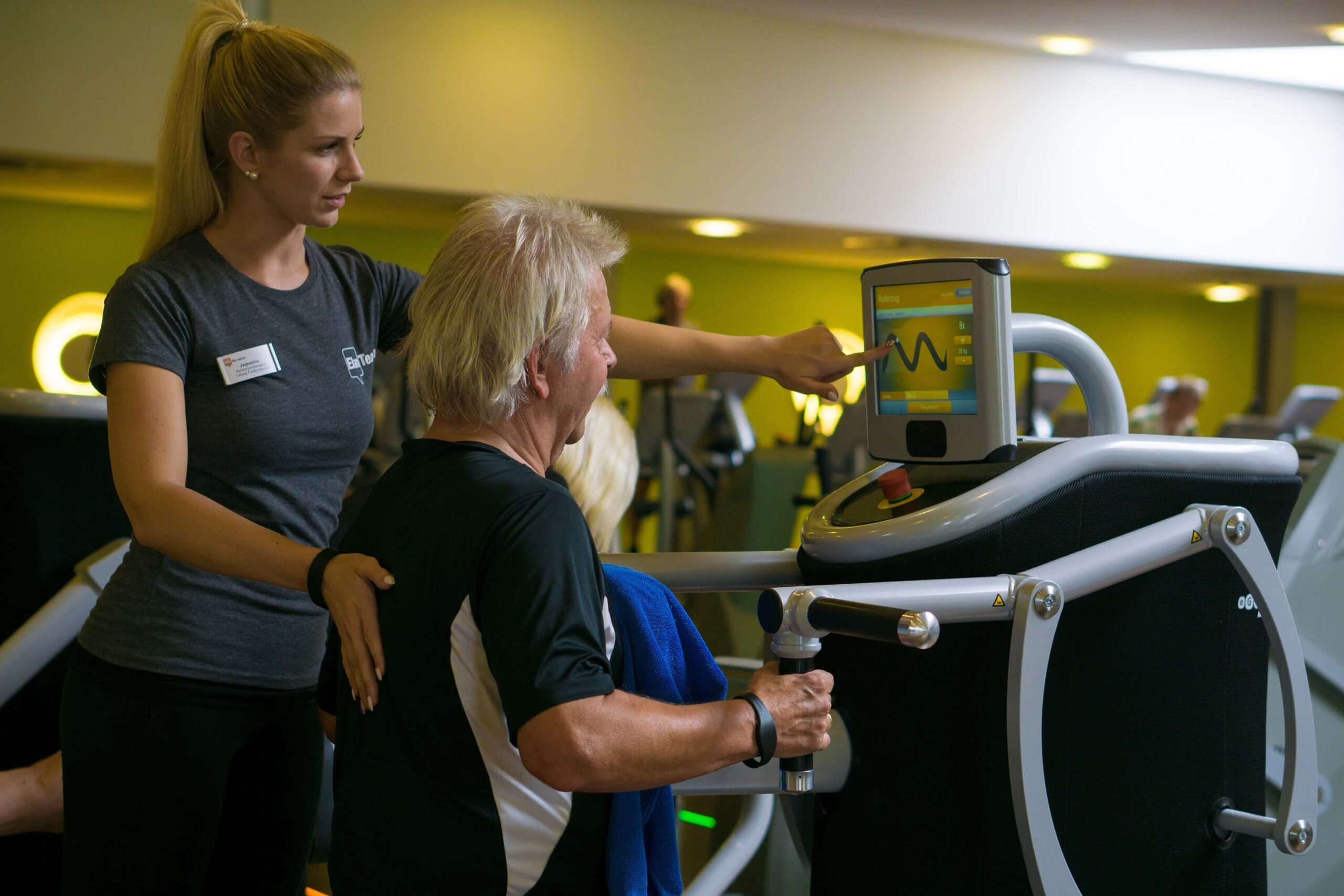 Trainerin stellt am EGYM Zirkel im Elan das Trainingsziel ein