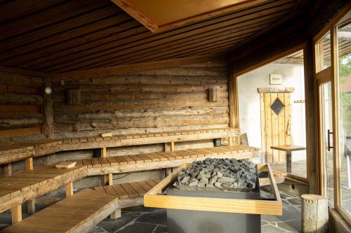 Rustikale Panoramasauna im ELAN Fitnessstudio mit Holzliegen, Saunaofen und großen Fenstern
